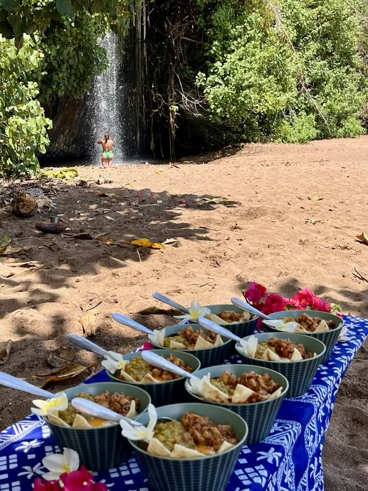 Table dressée sur la plage : plats servis en bols, au pied d'une cascade
