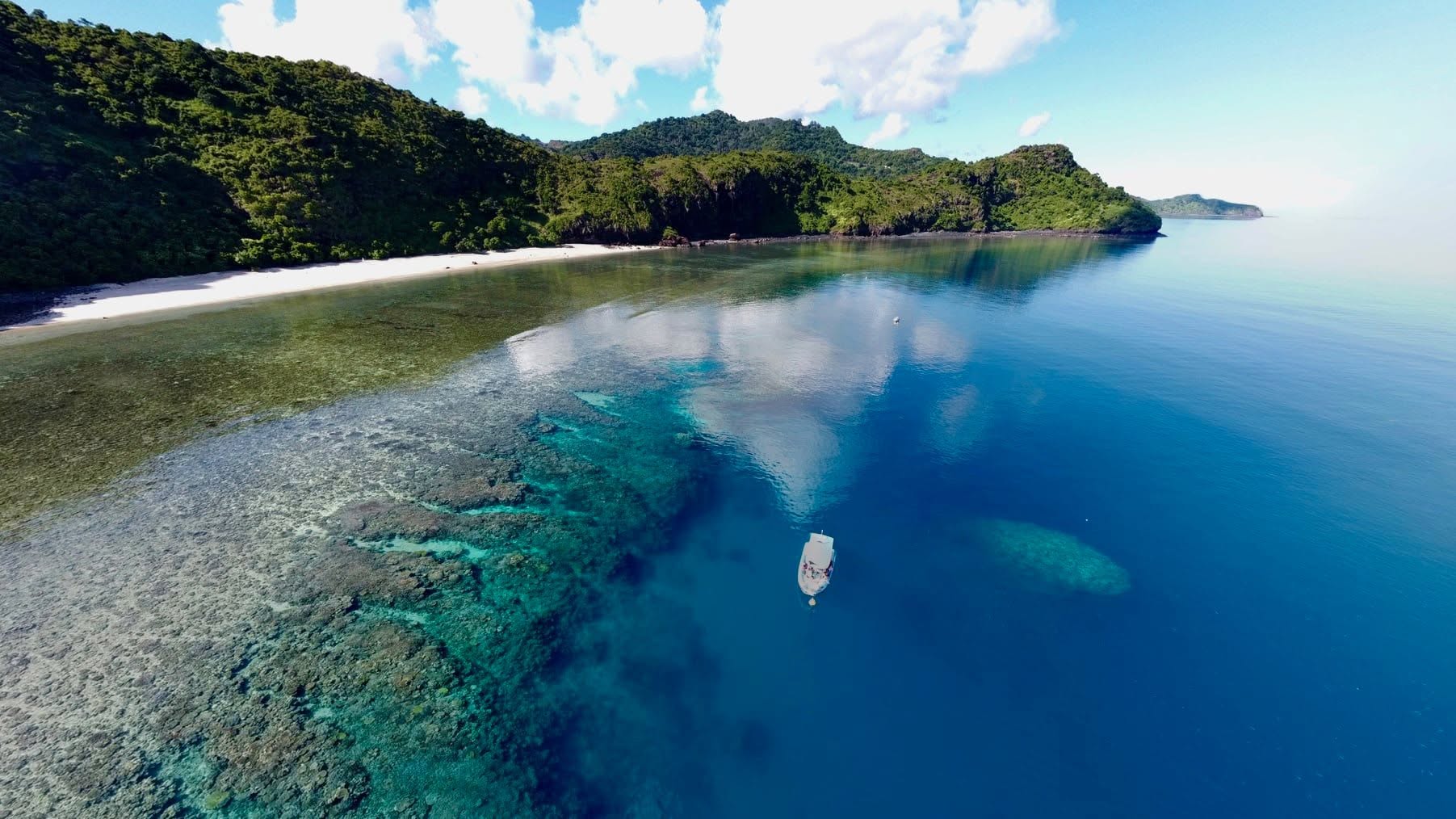 Vue aérienne du lagon de Mayotte : récif, plage et bateau au mouillage